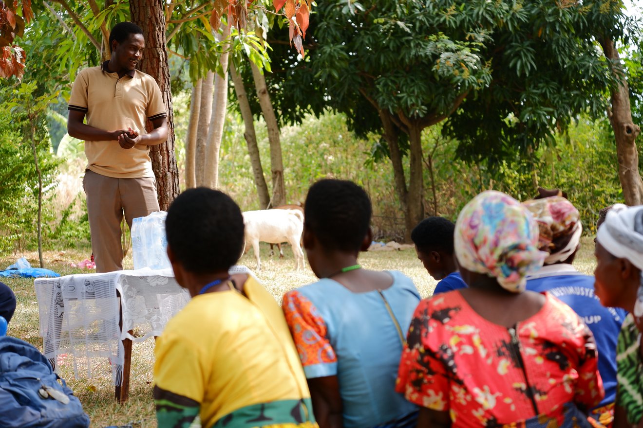 Eine Person spricht im Grünen vor mehreren Zuhörenden.