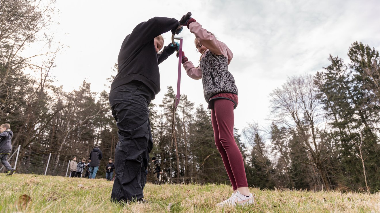 Zwei Kinder stechen ein Pflanzloch in die Erde
