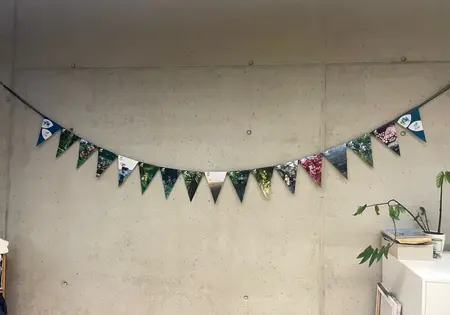 Eine Wimpelkette im PRIMAKLIMA-Design hängt an einer Wand.